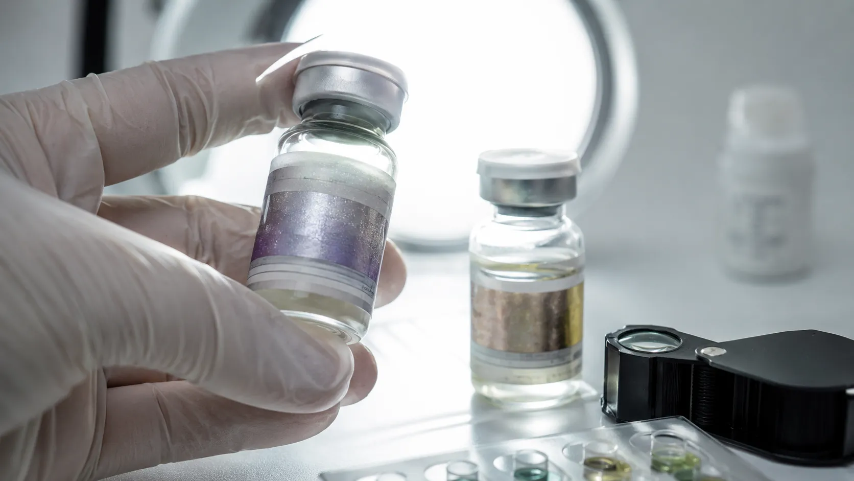 Gefälschte Steroide erkennen: die definitive Checkliste 3 Pharmavial unter klinischem Licht neben gefälschtem Gegenstück mit verschwommenem Hologramm – Sichtprüfung und Reagenztest-Kit zur Identifikation gefälschter und unterdosierter Steroide