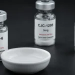 GHRP-6-lyophilisiertes-Forschungspeptid-Vial mit leerem-keramischen-Ramekin-Hunger-Appetit-Signal davor neben CJC-1295-GHRH-Analog-Stackingpartner-Vial im Hintergrund und Ipamorelin-Vergleichsvial-ohne-Appetitstimulations-Element rechts – Ghrelin-Rezeptor-GHS-R1a-GH-Sekretagog: starke-NPY-AgRP-Appetit-Stimulation Bulking-Vorteil vs Cutting-Nachteil, Saturation-Dose-100mcg, CJC-1295-Synergismus-Goldstandard, Ipamorelin-appetitfreie-Alternative