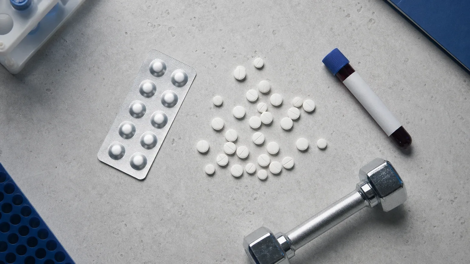 Tabletten, Kurzhantel und Blutröhrchen auf Stein – Anadrol Wirkung auf Masse, Kraft und Wassereinlagerung