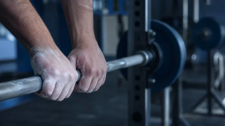 Hände mit Magnesia greifen eine Langhantel im Fitnessstudio – Steroid-Kur für Stärke